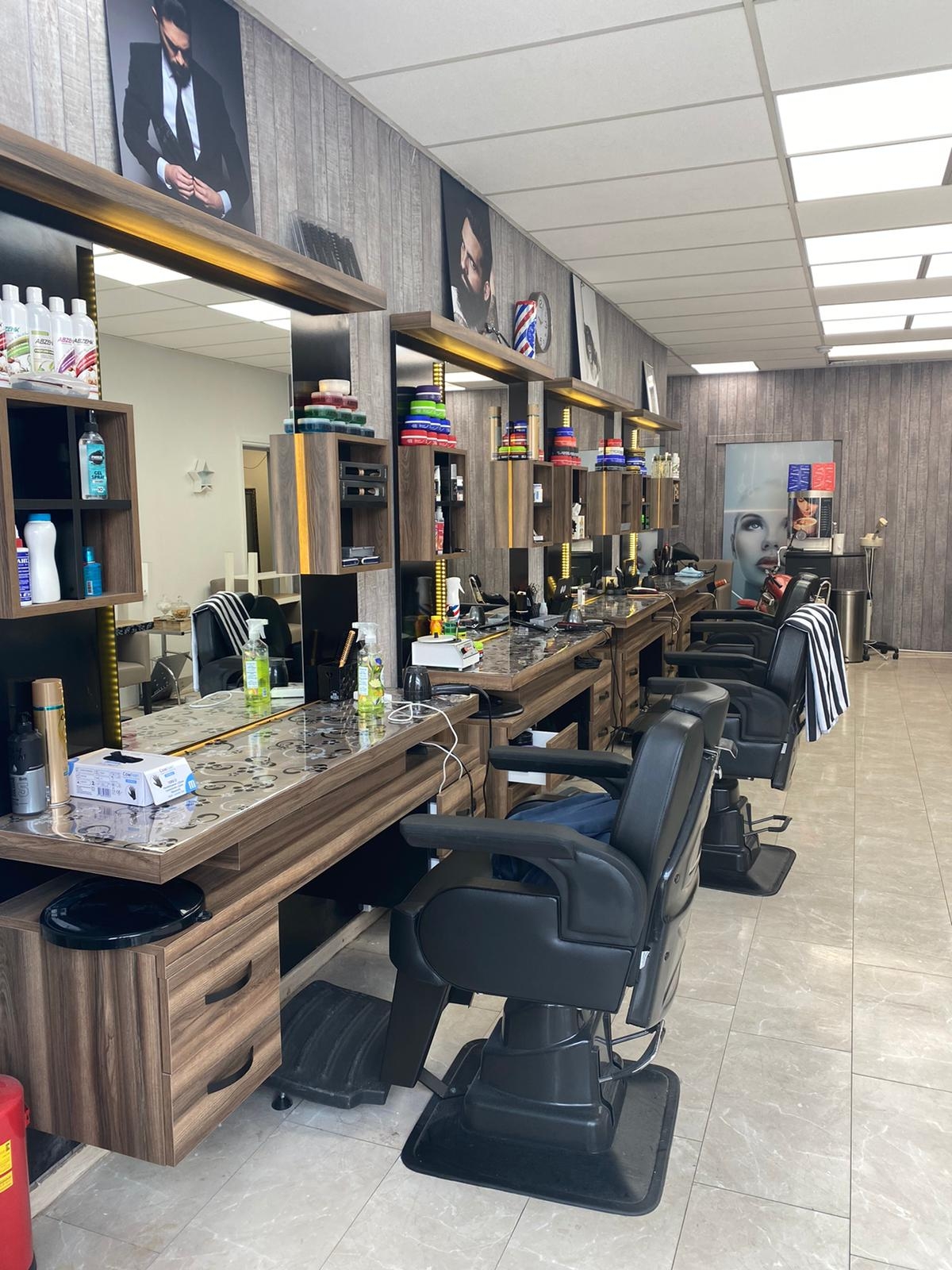 Binnen bij Armang barbershop: een rij kappersplaatsen met spiegels en zwarte barberstoelen